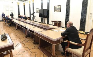 Putin at one end of ridiculously long table with officials at the other end at emergency economic meeting