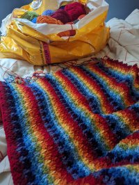 WIP rainbow striped crochet blanket and massive bag of yarn