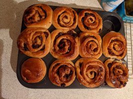 A baking tin of twirly fruit buns with one missing 