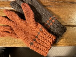 Brown and orange gloves. The brown glove has two rows of small crosses in orange, the orange glove has one row of small crosses in brown.