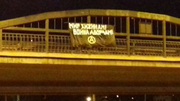 black banner on bridge with white Anarchy symbol and writing in Russian.jpg