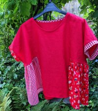 A red top with a gathered bottom half, made from assorted red fabrics. 