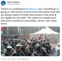 Uniformed men sit outside large tent in fenced area outside.