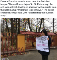 Young dark-haired woman holds up paper banner with Cyrillic writing.