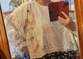 A very loose, short white blouse with big puffy sleeves, made of bits of embroidered and lacy fabric 