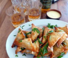 A plate piled with crispy haggis samosas sits in front of several poured glasses of whisky. Phwoar!  