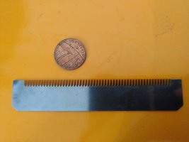 Picture of a removable mandoline blade next to a penny for scale