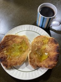 Two toasted butteries on a plate topped with lime marmalade, next to a cup of stovetop espresso.