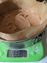 A cake tin on the scales, containing unbaked cake mixture. The scales read 666.