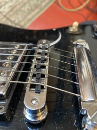 The picture shows a Gibson SG’s tune-o-matic bridge.  The black finish of the body shows up specs of dust and embarrasses me. I feel ashamed.