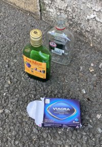 Empty bottles of spirits and a viagra packet on a pavement.