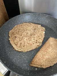 A frying pan has Staffordshire oatcakes filled with cheese sizzling away in it.