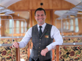 train interior, smiling check-waistcoated employee