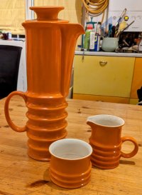 A very tall, ridged, tubular orange coffee pot, very 60s, with matching bowl and jug