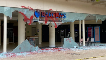 front of Barclays bank building with glass smashed and red paint