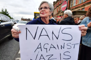 woman holding large sign saying NANS AGAINST NAZIS