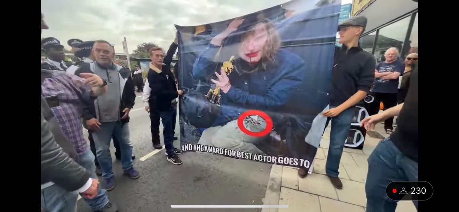 Far right ''anti-drag'' protestors at Honor Oak holding up a picture of a transwoman injured at an earlier protest captioned ''And the award for best actor goes to''