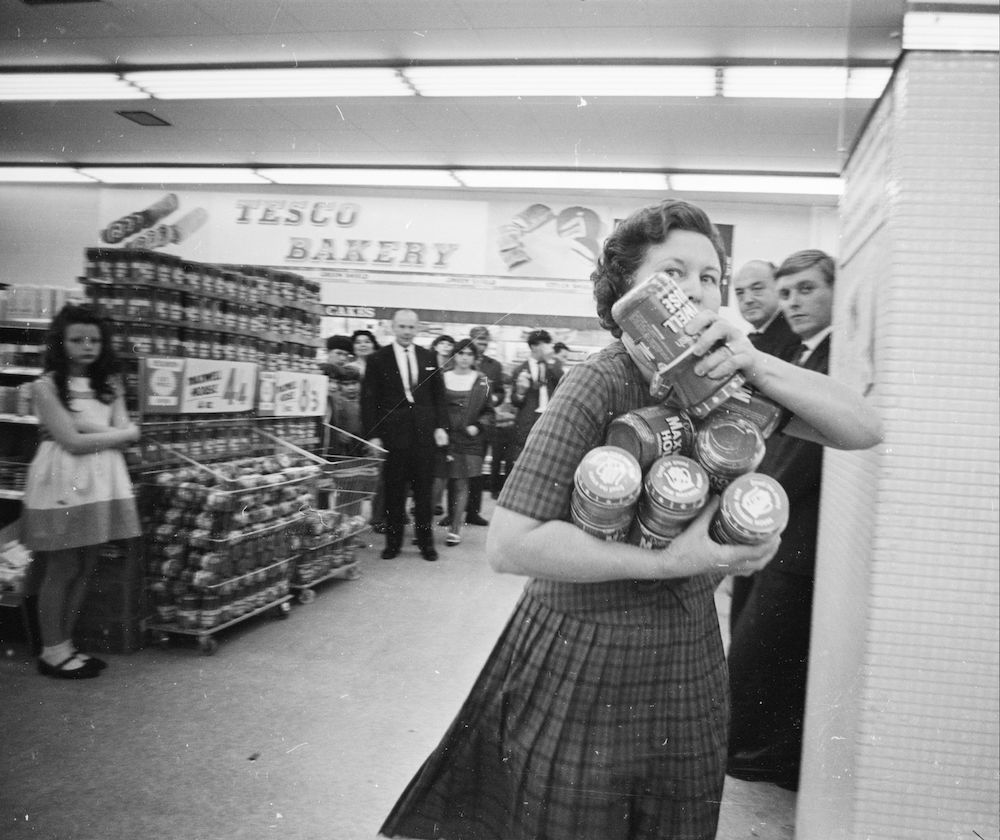 10th August 1966: Mrs Buzidragis, winner of a US supermarket sweep contest attempts to repeat her prize-winning feat in a London Tesco. She makes her way to the checkout counter with her arms full of Maxwell House coffee jars. (Photo by Terry Fincher/Express/Getty Images)