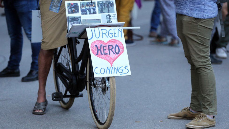 A cyclist rides a bike with a banner in support to far-right Belgian soldier Jürgen Conings on 29 May