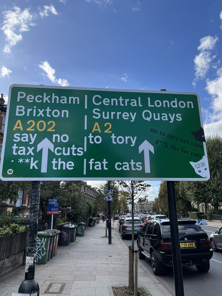 road direction sign with 'no to tory tax cuts f**k the fat cats' added